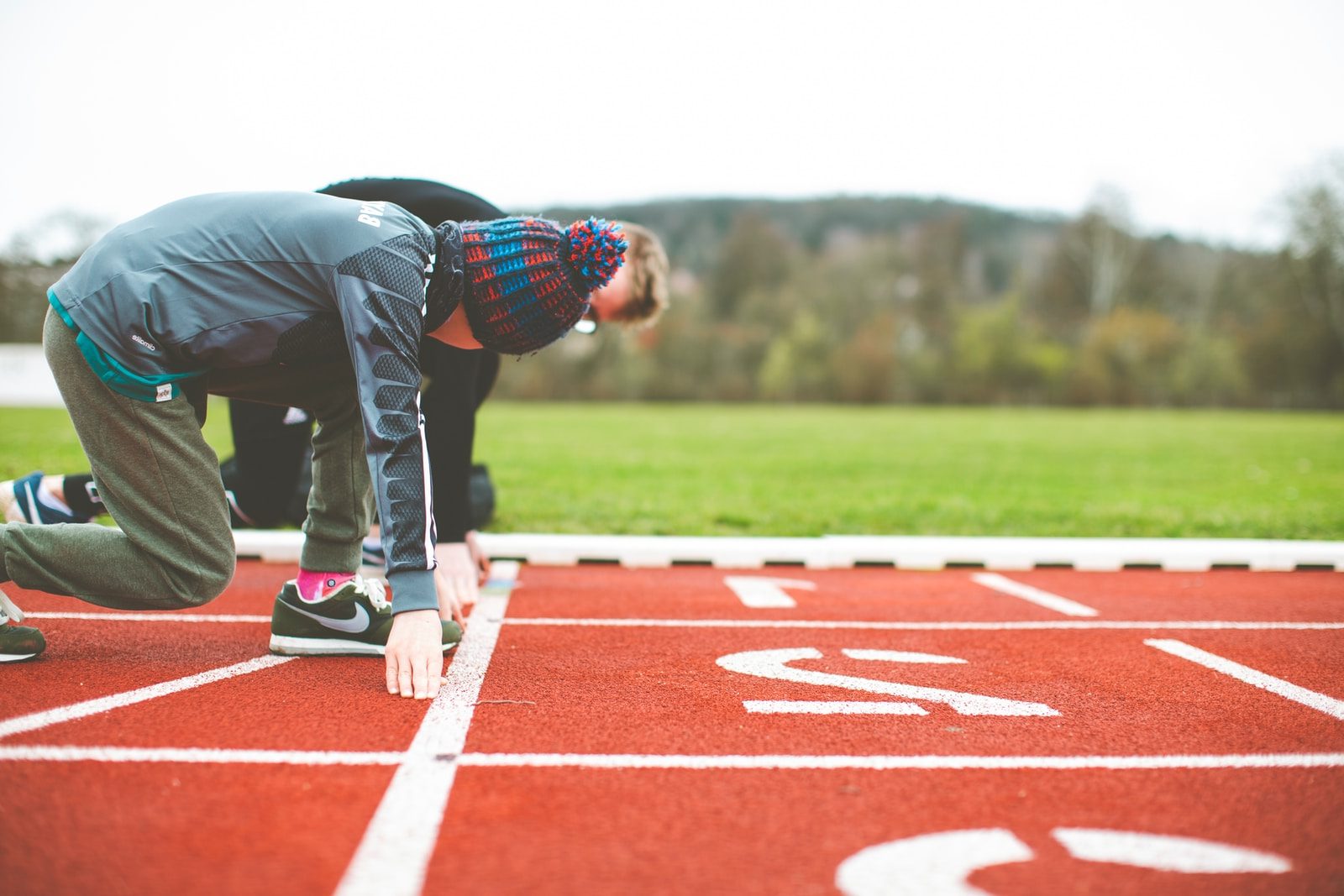 man in black and red plaid shirt and black pants standing on track field during daytime